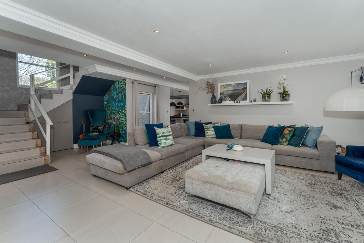 Spacious living room featuring tiled flooring, recessed lighting, crown molding, and an integrated staircase with under-stair storage.