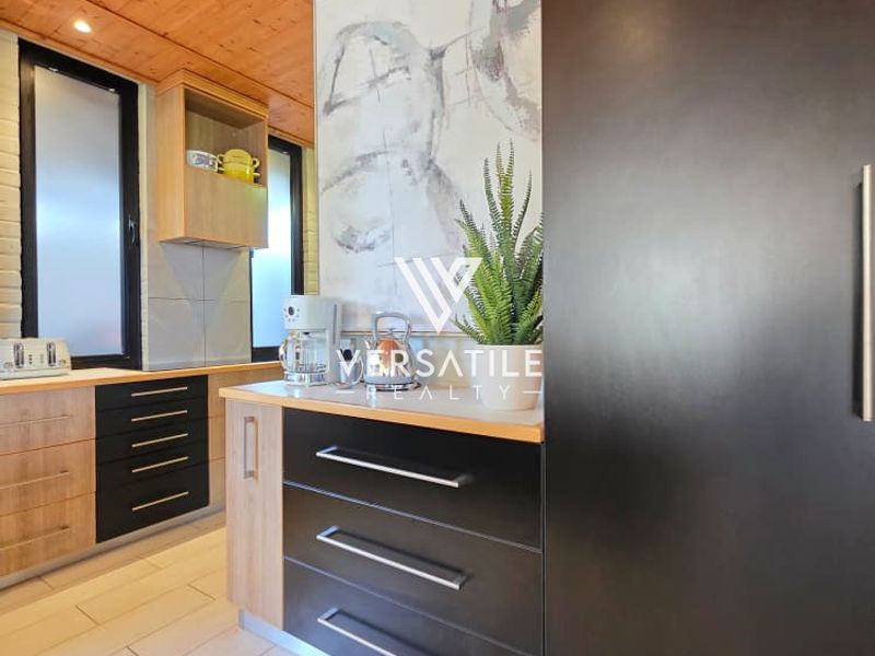 Modern kitchen featuring sleek two-tone cabinetry, timber-clad ceiling, and light-colored floor tiles, offering a contemporary and functional workspace.