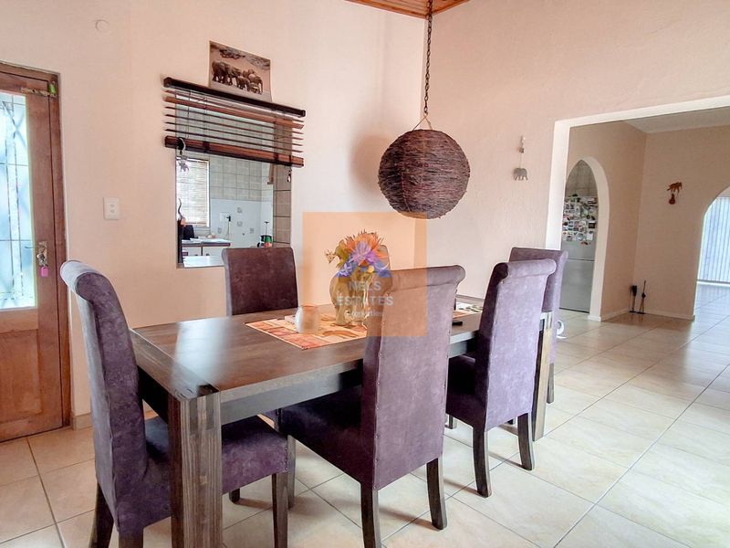 Dining room featuring tiled flooring, a serving hatch to the kitchen, and an arched entryway leading to adjacent living spaces.