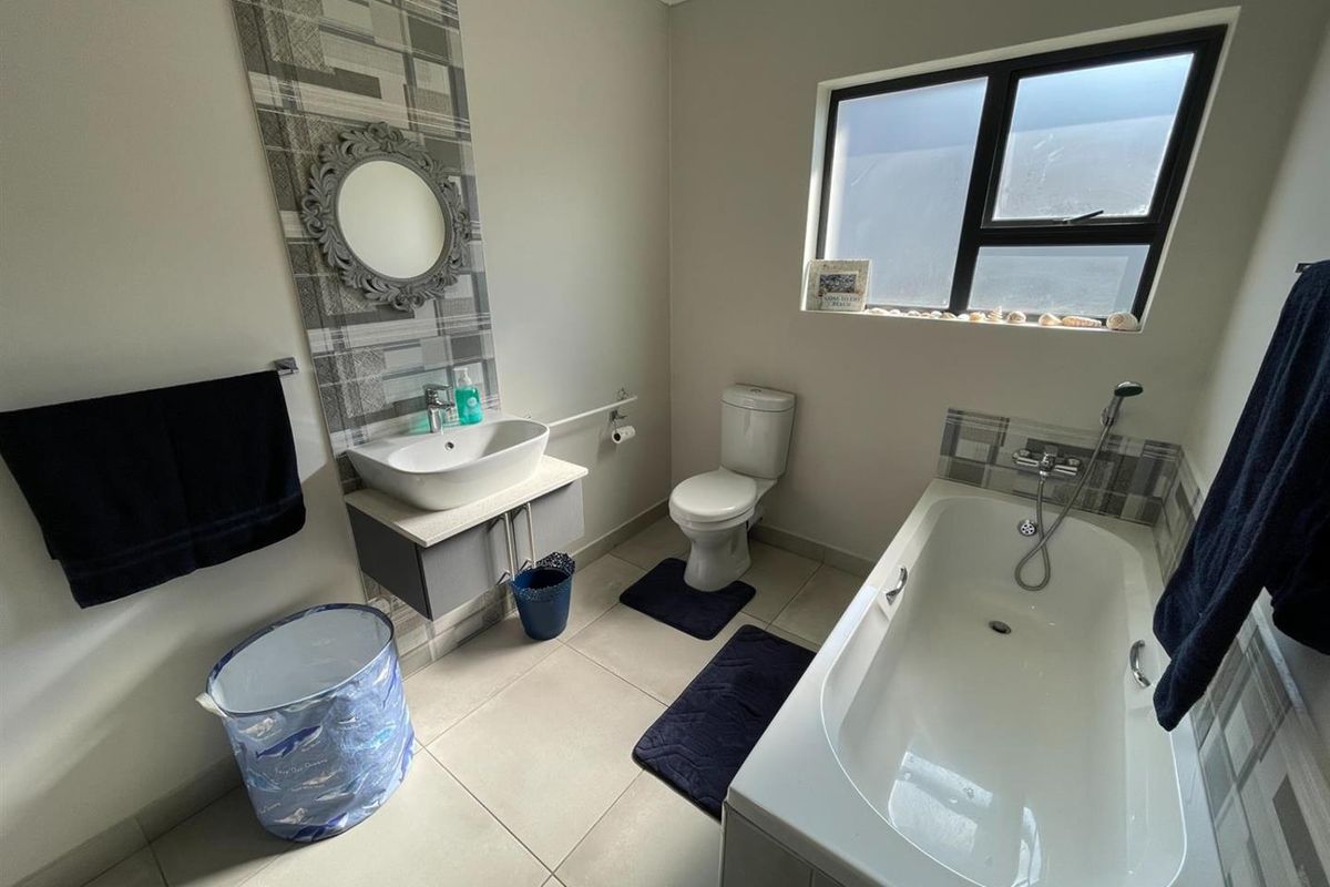 A modern bathroom featuring a floating vanity with a vessel sink, a built-in bathtub with shower mixer, and tiled flooring.