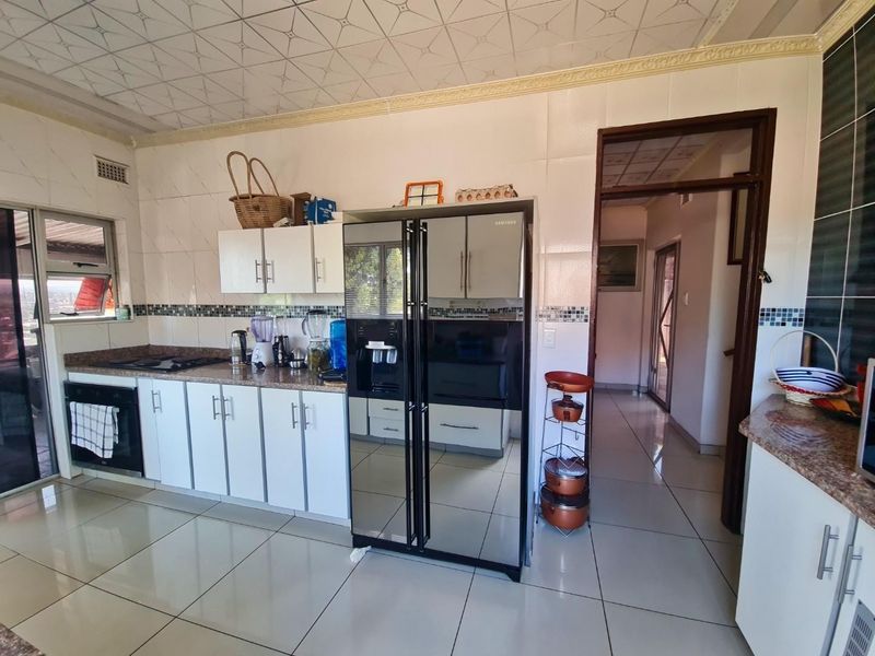 A functional kitchen featuring built-in cabinetry, granite countertops, integrated oven and hob, and tiled finishes throughout.