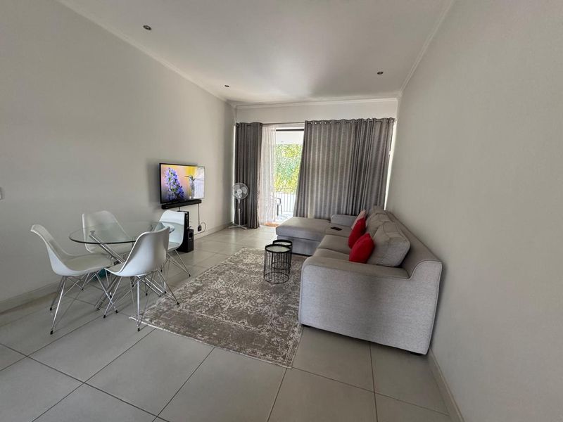Open-plan living and dining area featuring neutral tiled flooring, recessed lighting, and direct access to a balcony through a sliding glass door.