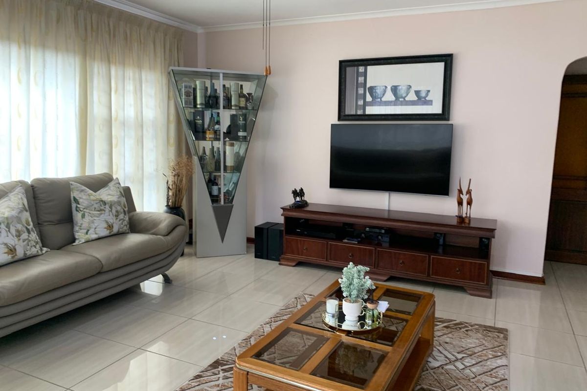 A well-maintained living room featuring neutral tiled flooring, a ceiling fan, and cove cornicing, providing a comfortable and functional space.