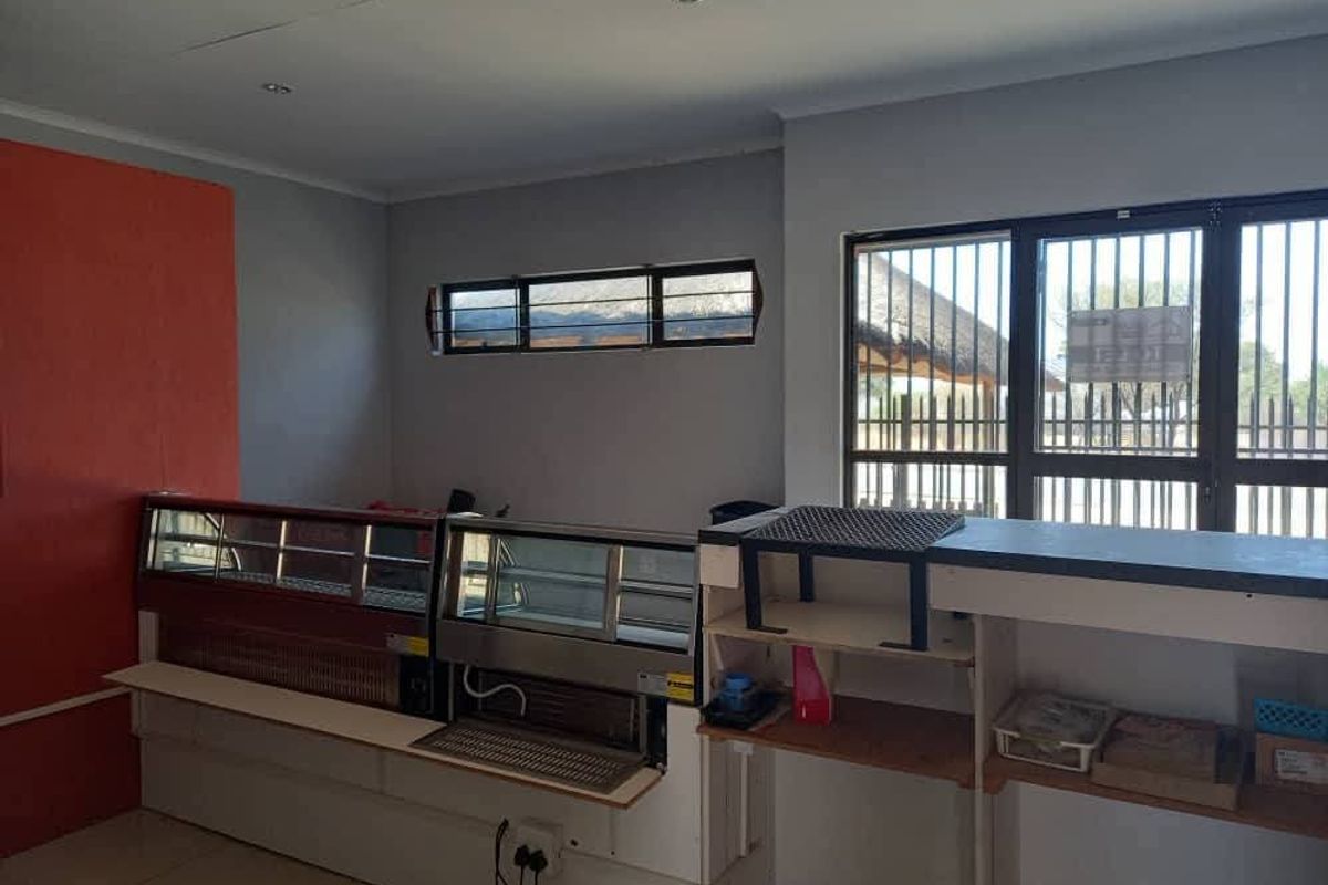 Commercial kitchen or service area featuring built-in display refrigeration units, a service counter, and security-barred windows.