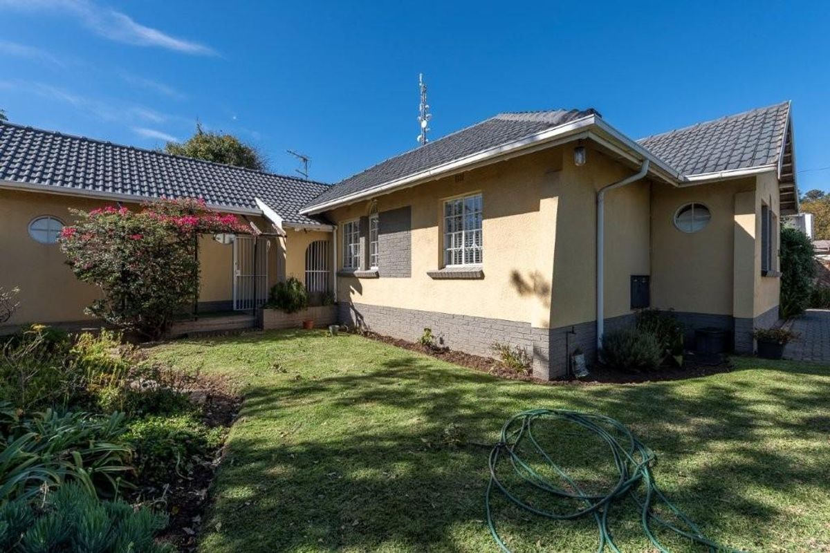 A view of the rear exterior of the house, featuring a tiled roof, plastered walls, and a small garden area.