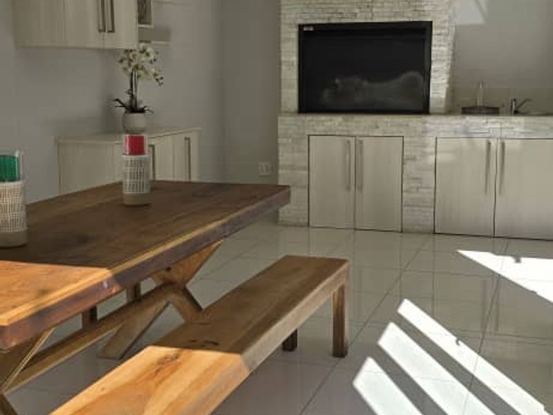 Open plan living area featuring a stone-clad built-in fireplace, modern cabinetry, and bright tiled flooring with ample natural light.