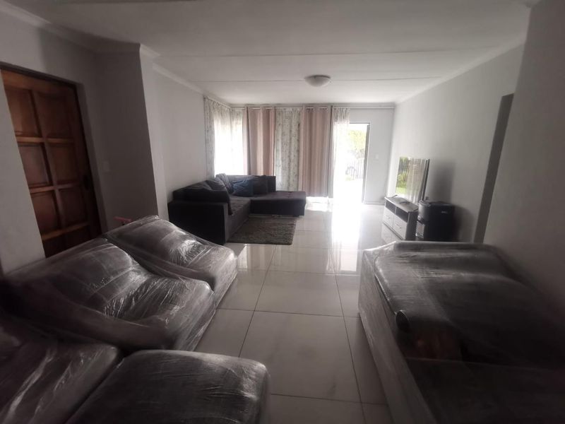Spacious living room featuring large format floor tiles and direct access to the outdoor area through a sliding door.