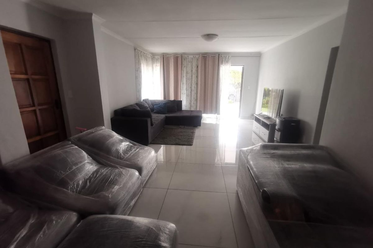 Spacious living room featuring large format floor tiles and direct access to the outdoor area through a sliding door.