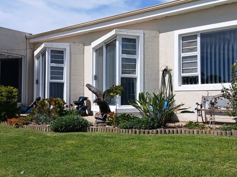 Rear exterior view of the townhouse featuring a paved patio, landscaped garden, bay windows, and a stone chimney detail.
