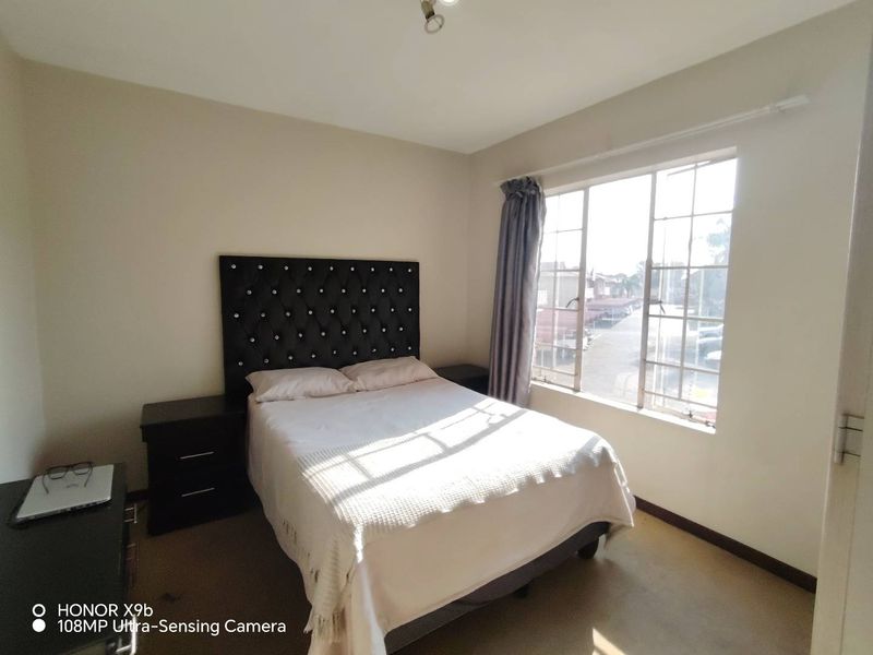 A functional bedroom featuring a large window with metal frames, providing natural light and a view of the surrounding area.