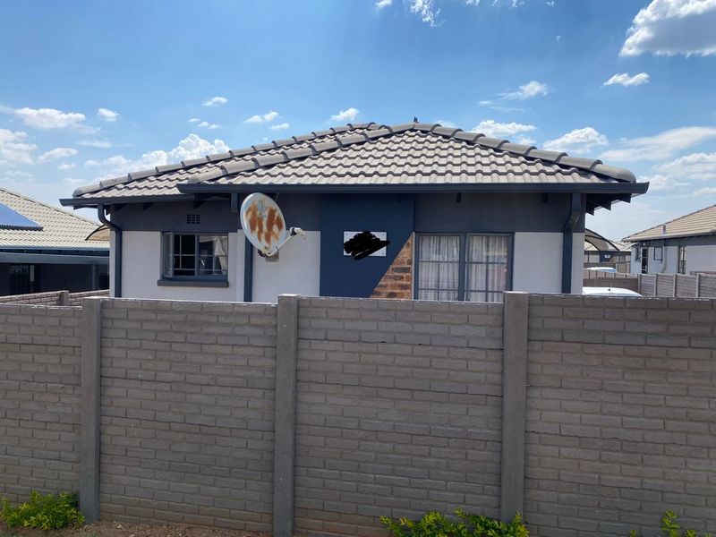 Rear view of a residential house featuring a tiled roof, aluminium window frames, and a secure precast concrete boundary wall.