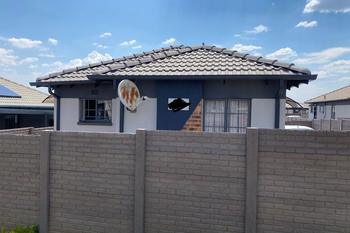 Rear view of a residential house featuring a tiled roof, aluminium window frames, and a secure precast concrete boundary wall.