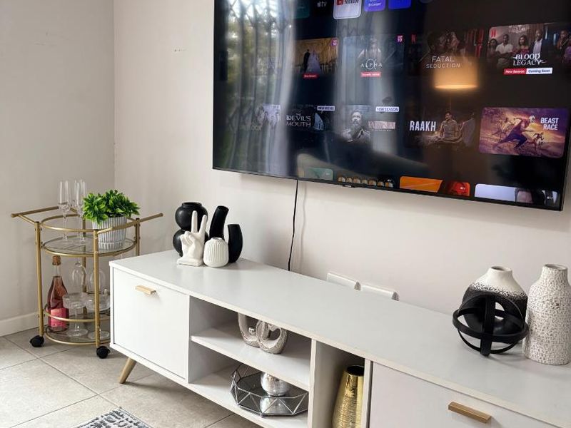 A modern living room area featuring neutral tiled flooring and a wall-mounted television setup.