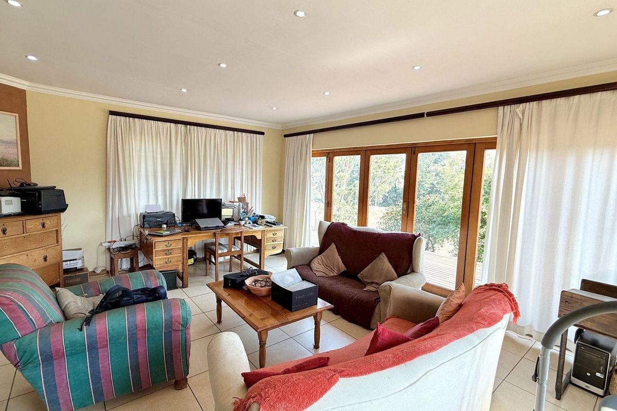 Spacious living area featuring tiled flooring, recessed ceiling lighting, and large wooden framed glass doors providing access to the outdoor space.