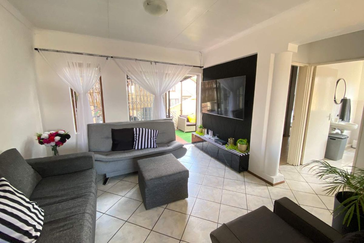 A bright living room featuring tiled flooring, a decorative black feature wall, and direct access to an outdoor patio area.