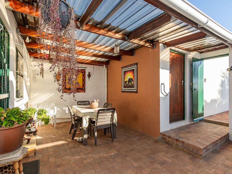 A covered outdoor patio area featuring brick paving, a timber pergola with translucent roofing, and direct access to the home via a timber door.