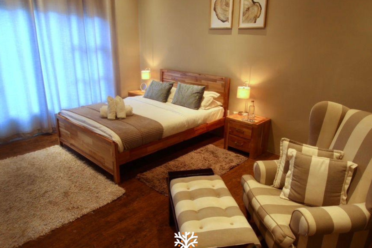 A well-maintained bedroom featuring warm-toned walls, timber flooring, and large windows with curtains, creating a comfortable and inviting living space.