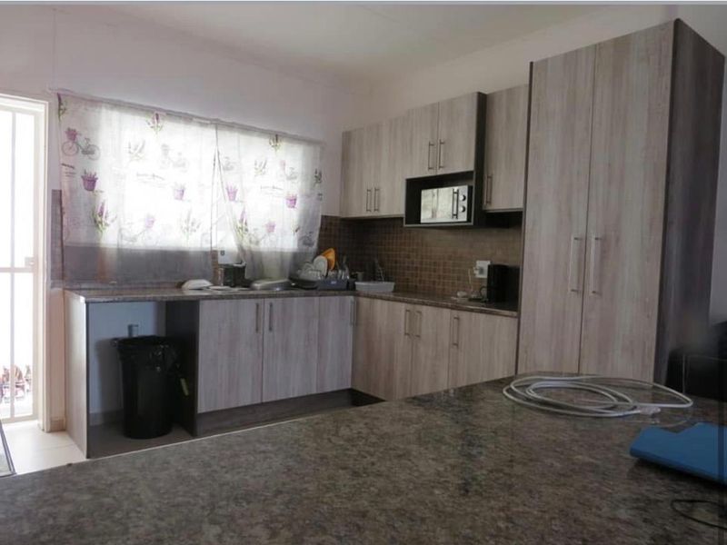 Functional kitchen featuring light wood-grain cabinetry, granite countertops, a mosaic tile backsplash, and a convenient kitchen island for additional workspace.