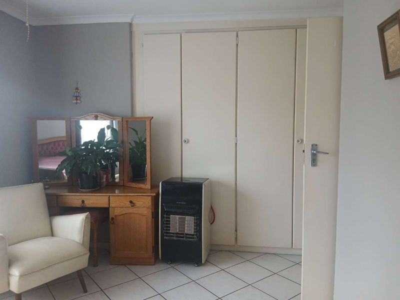 A bedroom featuring built-in cupboards and tiled flooring, providing a functional space with neutral wall finishes.