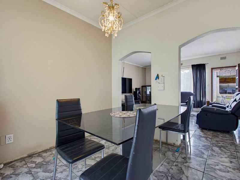 Dining area featuring tiled flooring and arched doorways leading to adjacent living spaces, with coved cornicing and neutral wall finishes.