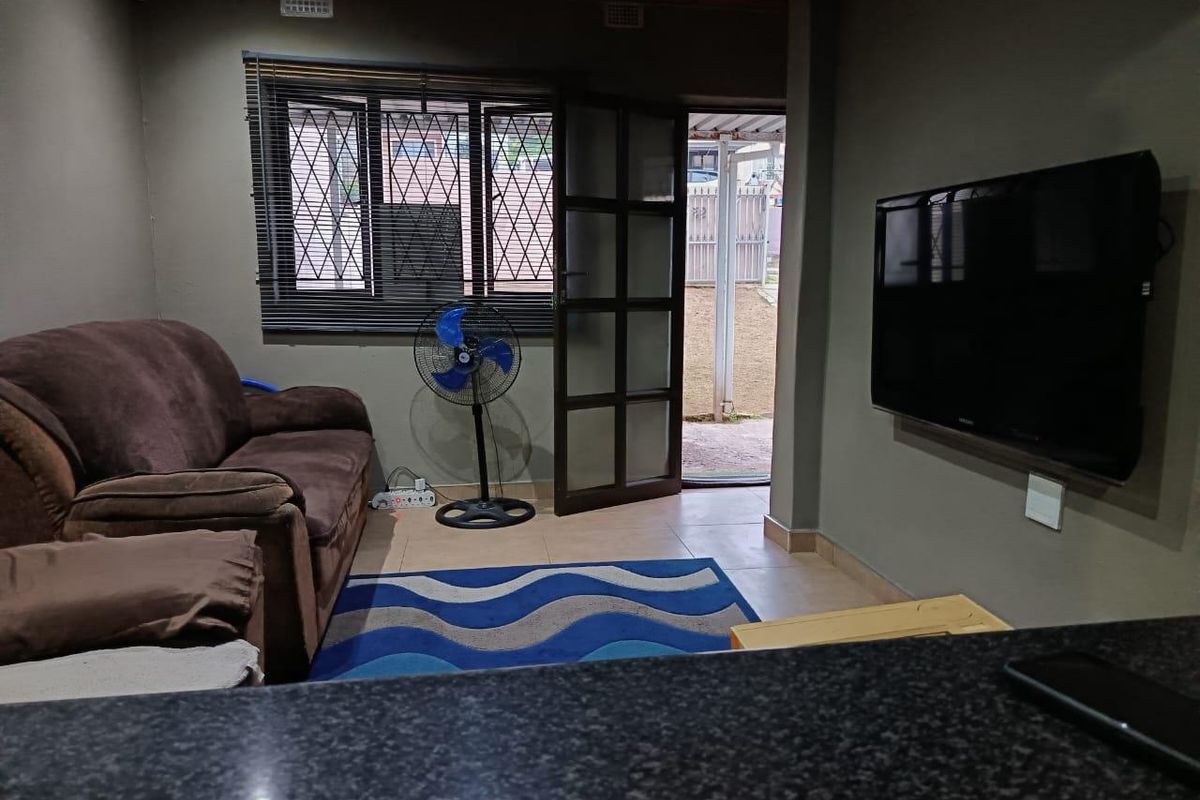 A living room featuring tiled flooring, a timber ceiling, and direct access to the exterior through a security-fitted door.