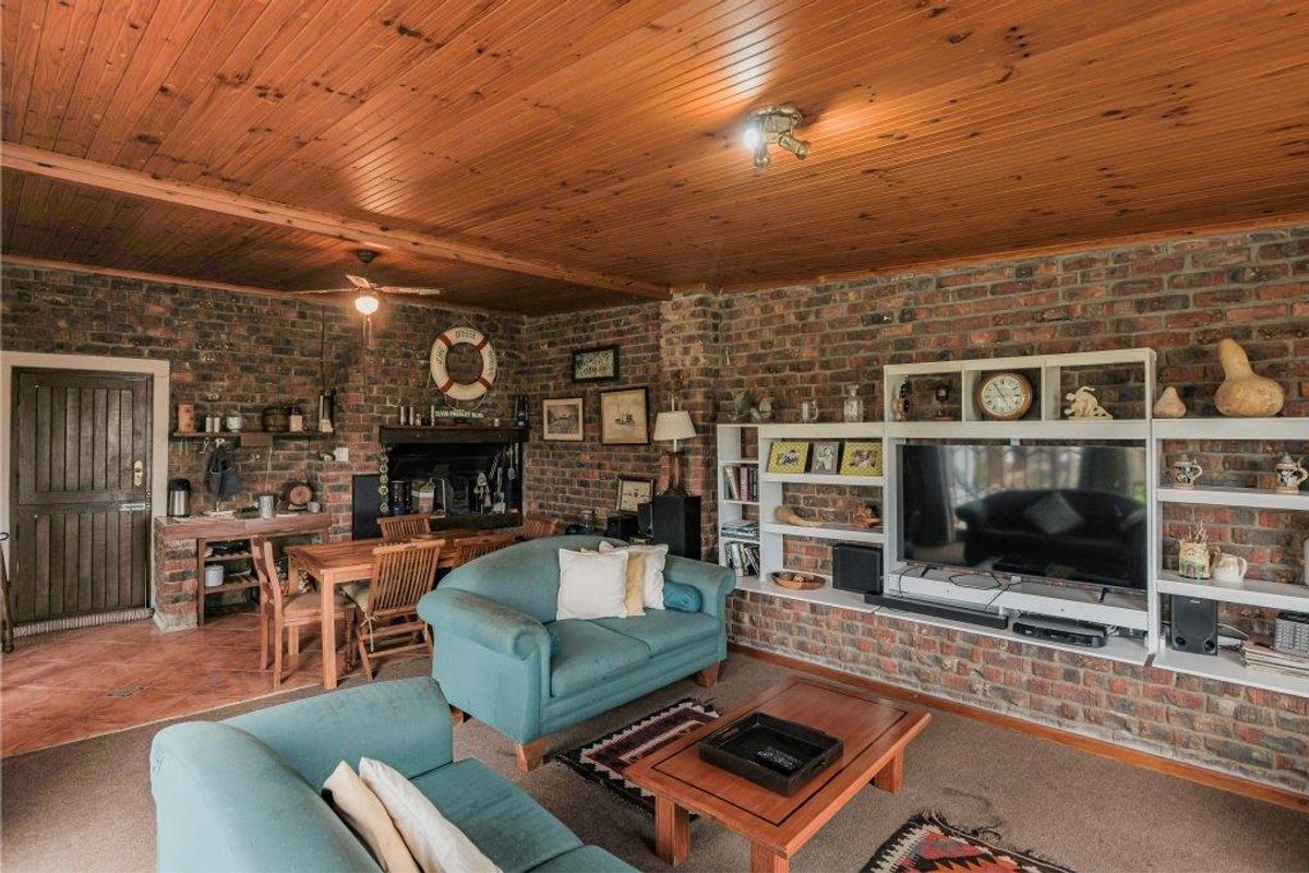 Spacious living room featuring exposed brick walls, a timber-clad ceiling, and a built-in fireplace, creating a rustic and cozy atmosphere.