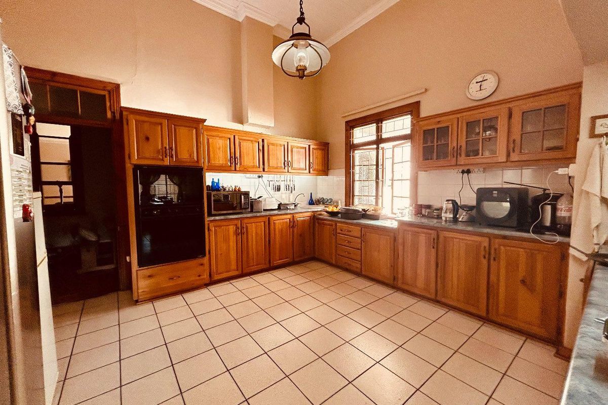 A spacious kitchen featuring traditional wooden cabinetry, tiled flooring, and a built-in oven, offering a functional layout with ample storage and counter space.