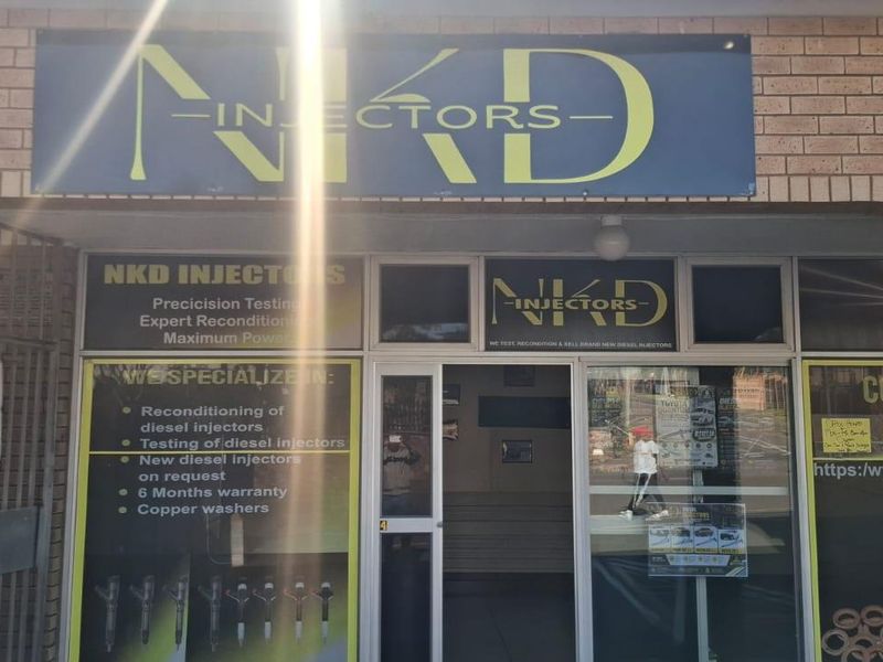 Front entrance of a commercial business premises featuring brick facade, glass door, and prominent signage.