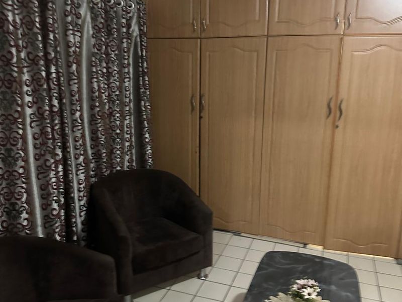 A bedroom featuring extensive built-in wooden cabinetry, tiled flooring, and a wall-mounted air conditioning unit.