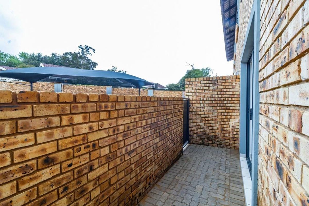 A side walkway featuring face brick walls and paved flooring, providing access to the property via a sliding glass door.
