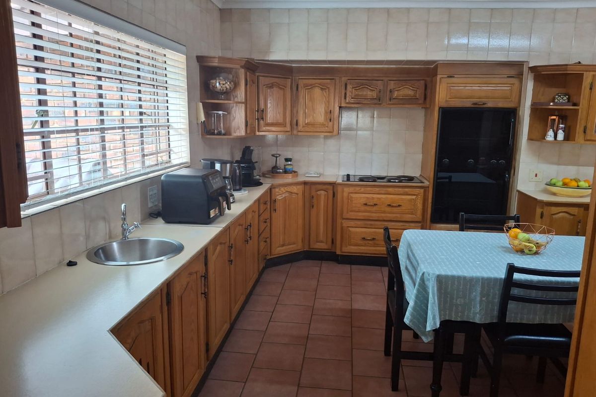 A functional kitchen featuring traditional wooden cabinetry, built-in oven, hob, and tiled finishes, offering a classic layout with ample storage space.
