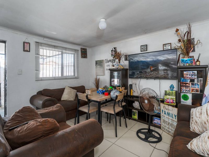 A compact living area featuring tiled flooring and a window with venetian blinds, offering a functional space for daily living.