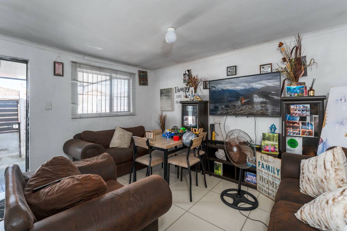A compact living area featuring tiled flooring and a window with venetian blinds, offering a functional space for daily living.