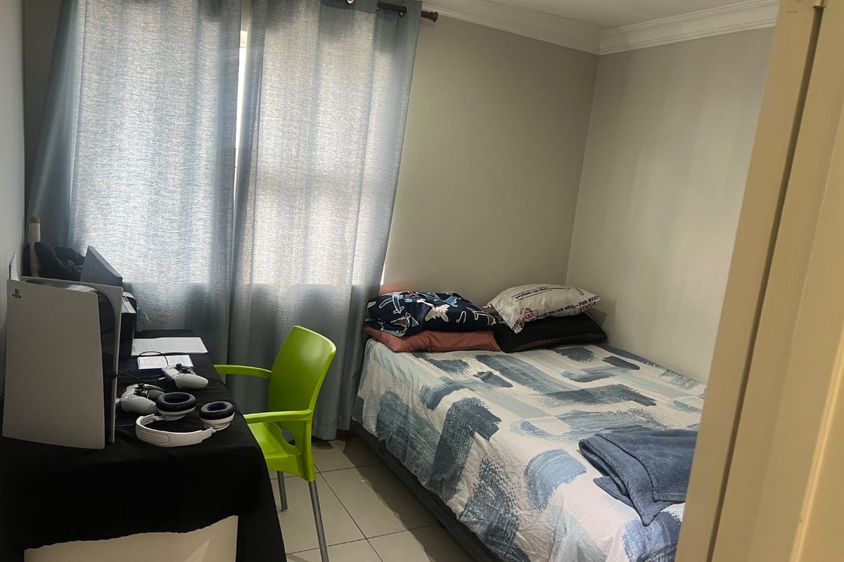 A compact bedroom featuring tiled flooring and neutral wall finishes, suitable for a single bed and workspace setup.