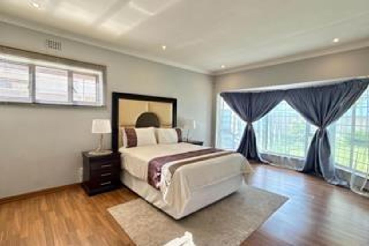 Spacious bedroom featuring wood-look flooring, recessed ceiling lighting, and a large bay window that provides ample natural light.