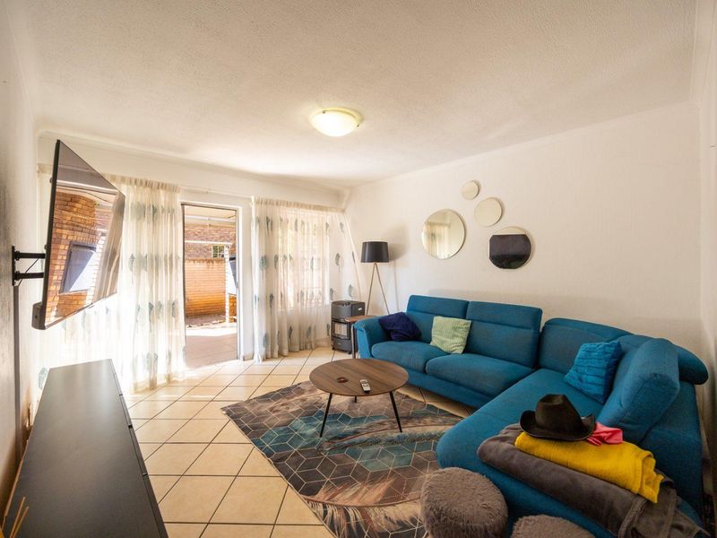 A bright living room featuring tiled flooring and a sliding glass door providing access to an outdoor patio area.