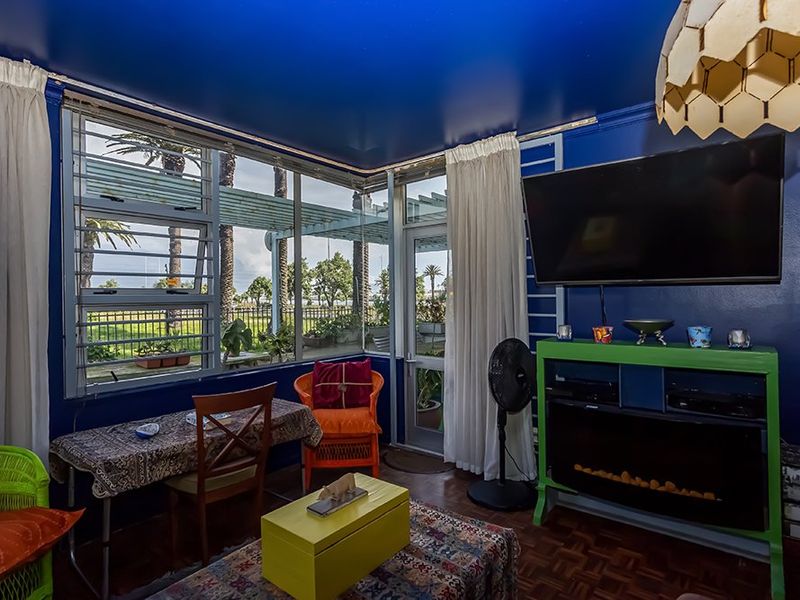 Living room featuring parquet flooring, large corner windows with garden views, and a built-in electric fireplace.
