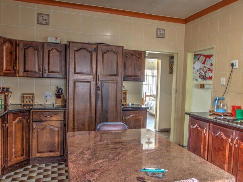 A traditional kitchen featuring dark wood cabinetry, granite countertops, and a tiled backsplash, offering a functional layout with potential for modern updates.