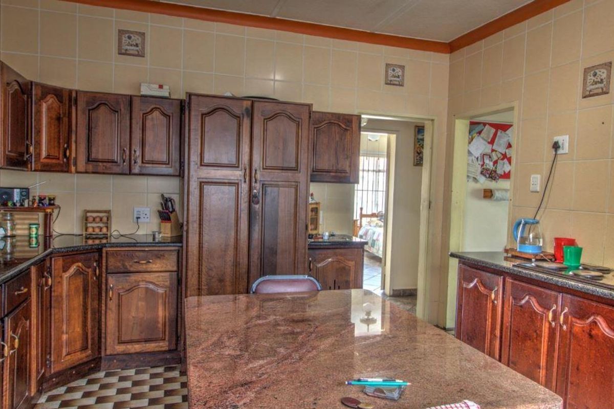 A traditional kitchen featuring dark wood cabinetry, granite countertops, and a tiled backsplash, offering a functional layout with potential for modern updates.
