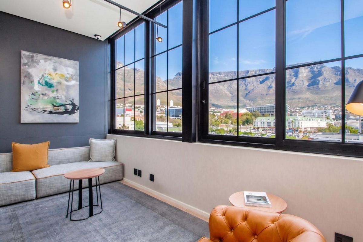 Modern living area featuring expansive black-framed windows with stunning mountain views, track lighting, and a contemporary aesthetic.