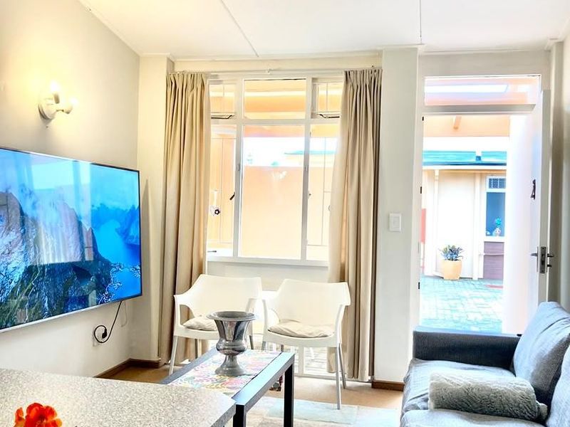 A bright living room featuring a large window, wall-mounted lighting, and direct access to an outdoor patio area.