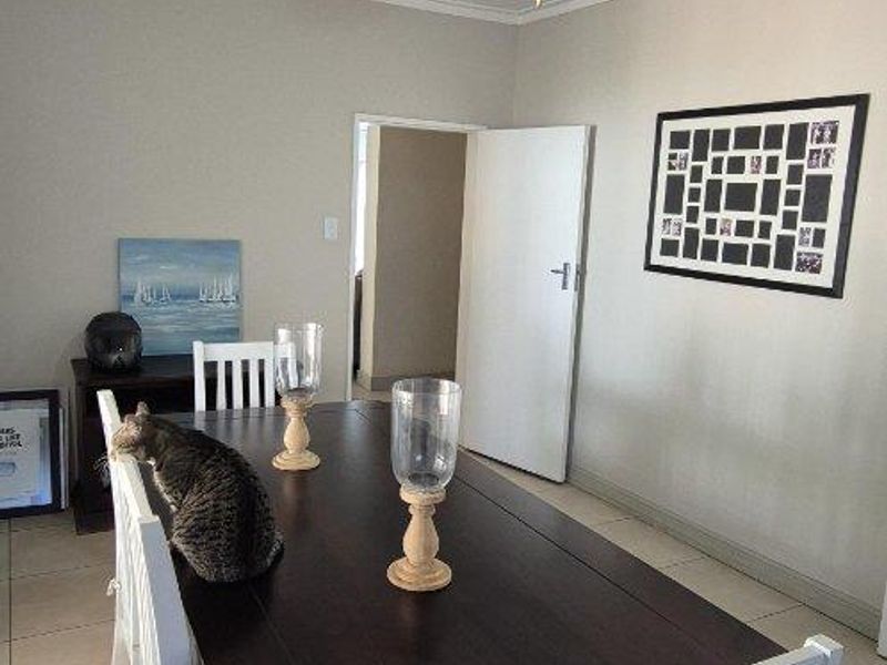 A well-maintained dining room featuring neutral tiled flooring, coved cornicing, and a central ceiling fan.