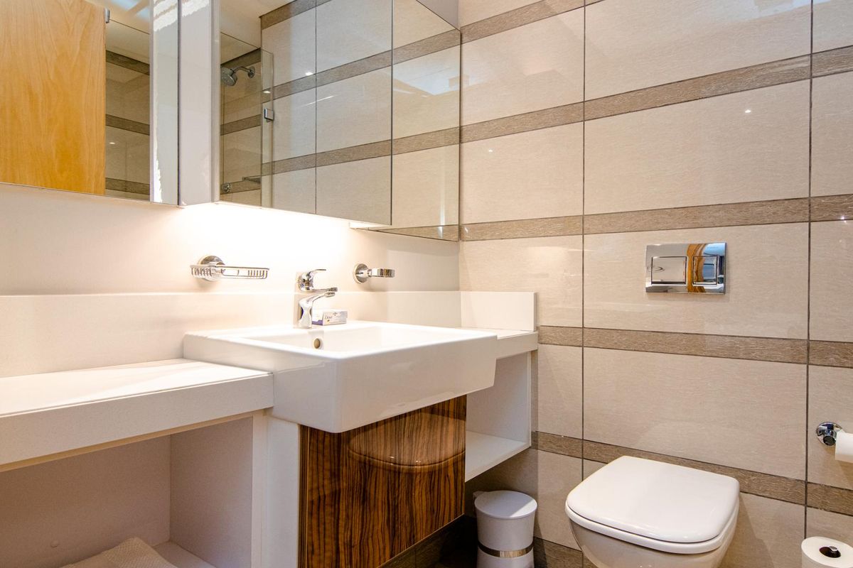 Modern bathroom featuring a wall-mounted vanity with integrated basin, mirrored cabinetry, and a wall-hung toilet with sleek tiled finishes.