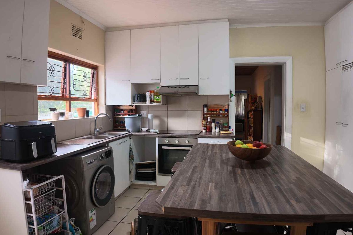 Functional kitchen featuring white cabinetry, laminate countertops, integrated oven and hob, and tiled flooring with a central island workspace.