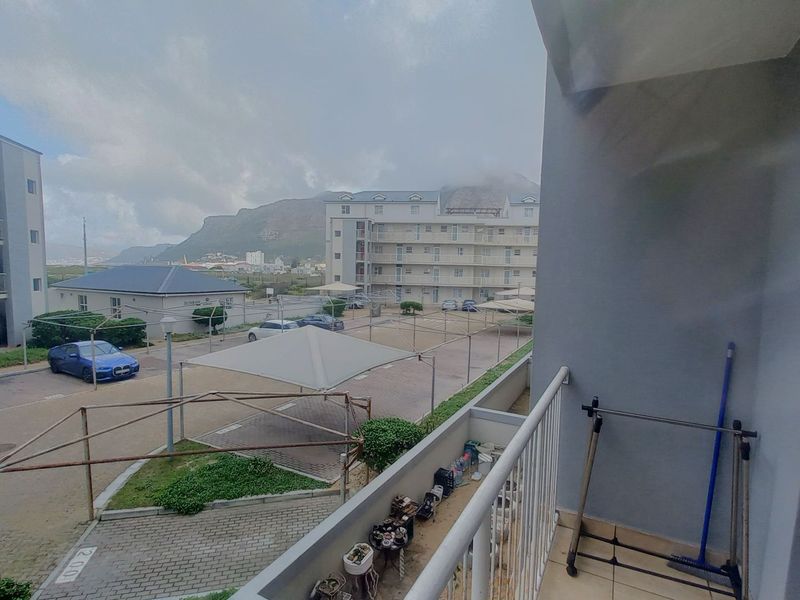 A balcony overlooking the apartment complex parking area and surrounding mountain landscape.