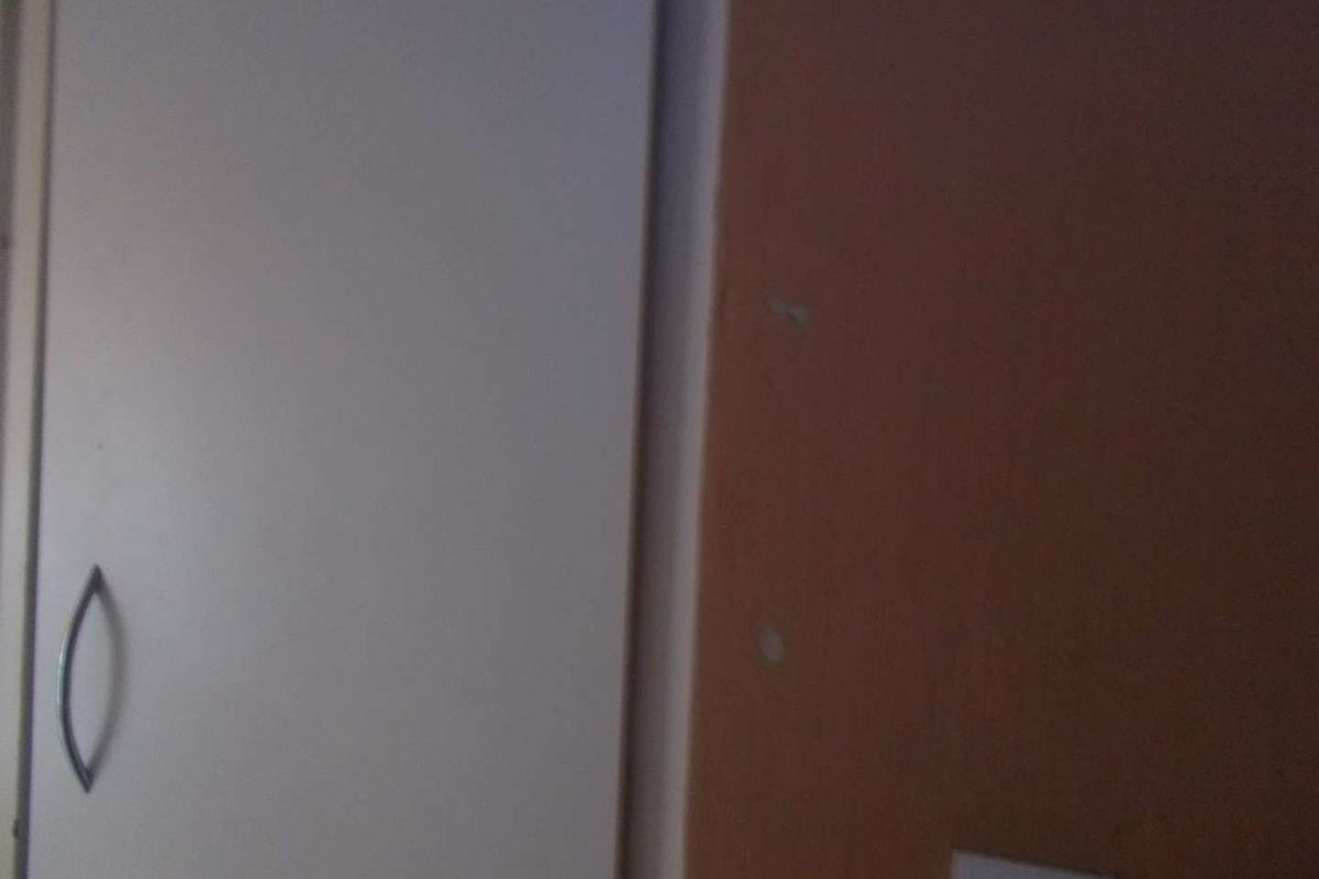 A close-up view of a built-in wardrobe door and adjacent wall surface showing signs of wear.