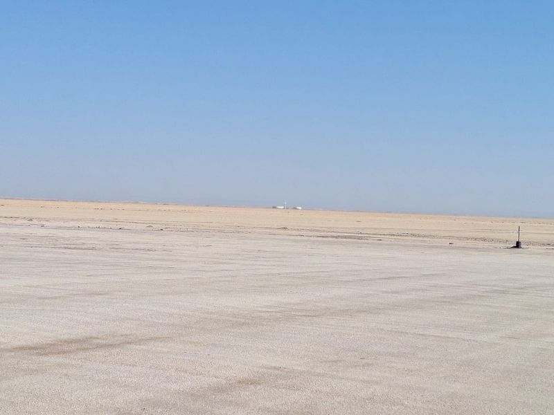 A wide, flat, undeveloped industrial land parcel with a clear horizon and sparse ground cover.