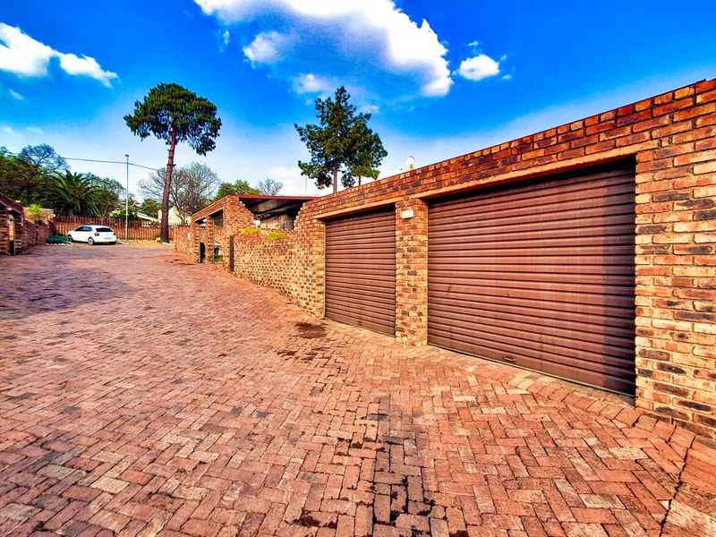 Exterior view of a double garage with roller doors and a brick-paved driveway in a cluster property setting.