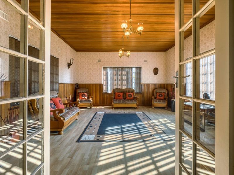 Spacious living room featuring warm timber ceiling and wall paneling, accessed through classic French doors with abundant natural light.