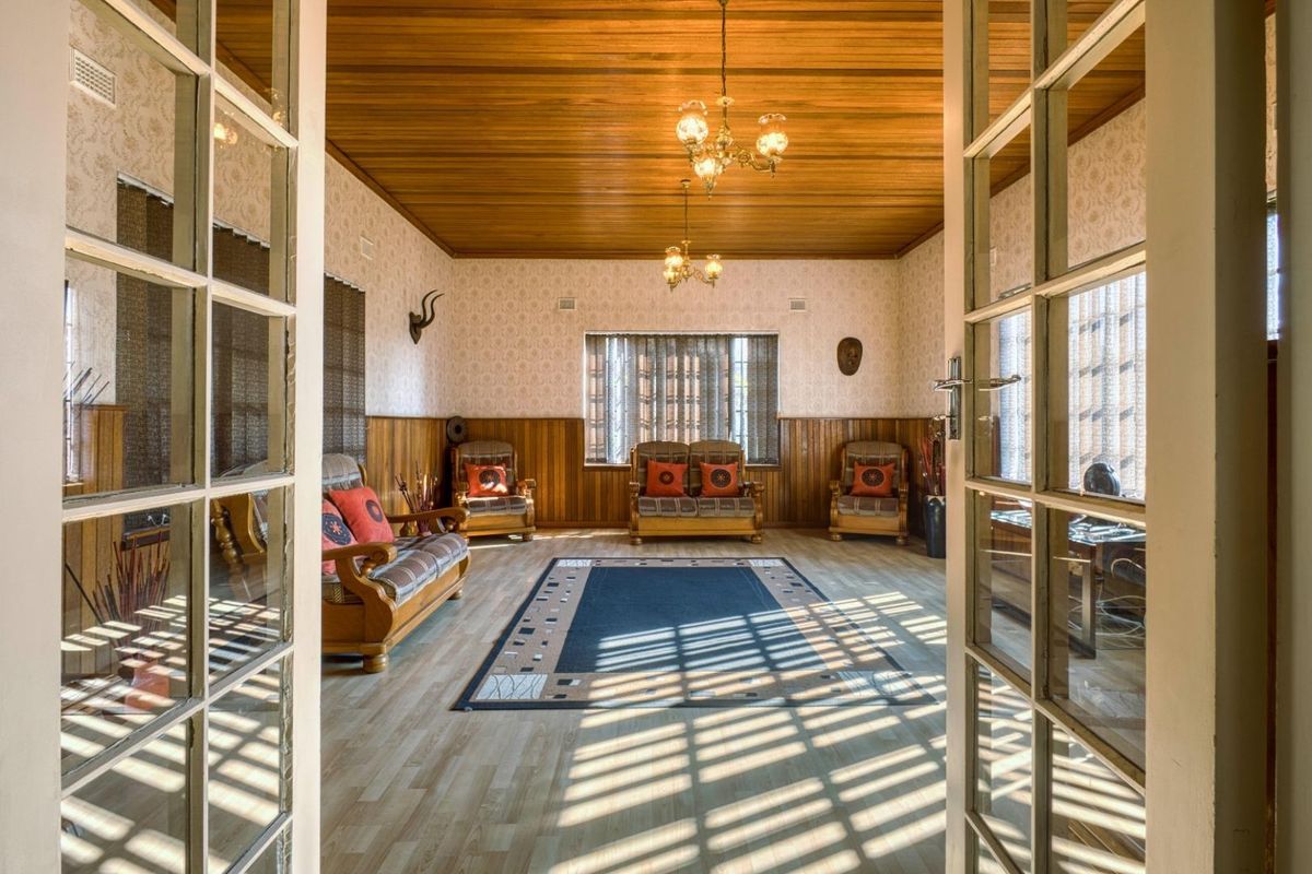 Spacious living room featuring warm timber ceiling and wall paneling, accessed through classic French doors with abundant natural light.